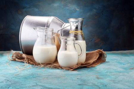 A jug of milk and glass of milk on a wooden table.