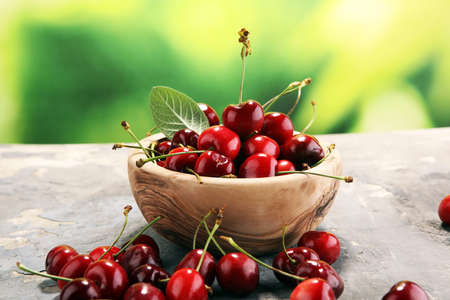 Cherry. Red fresh Cherries in bowl and a bunch of cherries on the table .の写真素材