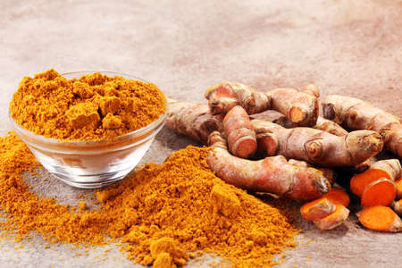 Turmeric powder and fresh turmeric on grey background.の写真素材