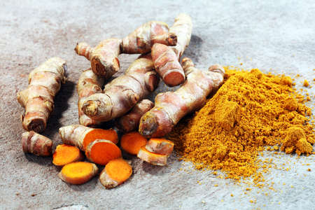 Turmeric powder and fresh turmeric on grey background.の写真素材