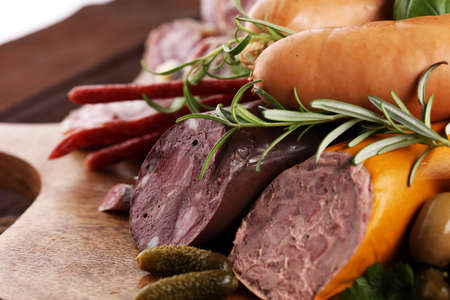 Food tray with delicious salami, ham,  fresh sausages, cucumber and herbs. Meat platter with selectionの写真素材