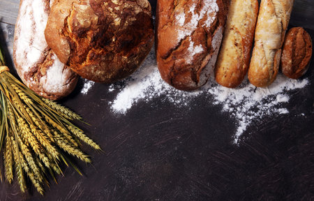 Different kinds of bread and bread rolls on board from above. Kitchen or bakery poster design.