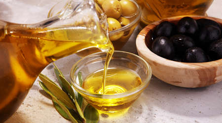 Bottle virgin olive oil and oil in a bowl with some olives.の写真素材