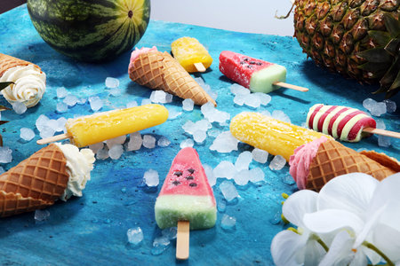 Vanilla frozen yogurt or soft ice cream in waffle cone and Colorful popsicle with tropical fruits