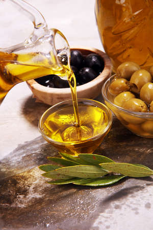 Bottle virgin olive oil and oil in a bowl with some olives.の写真素材