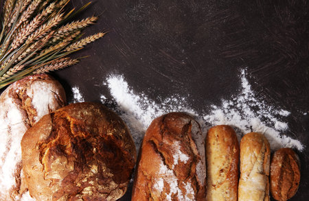 Different kinds of bread and bread rolls on board from above. Kitchen or bakery poster design.