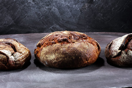 Different kinds of bread and bread rolls on board from above. Kitchen or bakery poster design.の写真素材