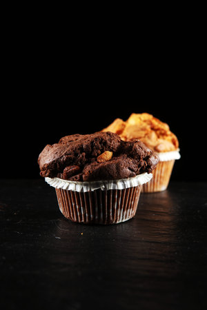 Chocolate muffin and nut muffin, homemade bakery on dark background