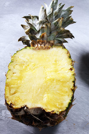Pineapple and a half of pineapple ruit. vegan delicious snack on white stone table.