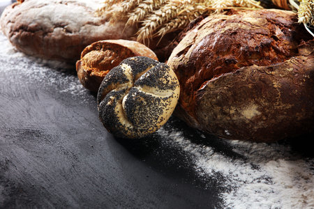 Different kinds of bread and bread rolls on board from above. Kitchen or bakery poster design.