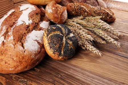 Different kinds of bread and bread rolls on board from above. Kitchen or bakery poster design.の写真素材
