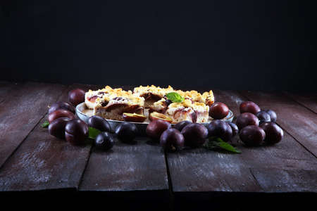 Rustic plum cake on wooden background with plums aroundの写真素材