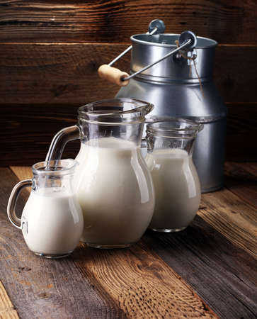A jug of milk and glass of milk on a wooden table.の写真素材