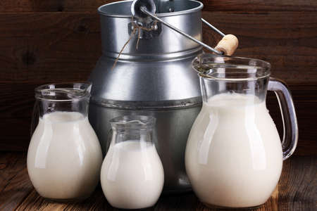 A jug of milk and glass of milk on a wooden table.の写真素材