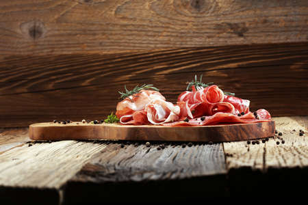Food tray with delicious salami, coppa,  fresh sausages and herbs. Meat platter with selection.の写真素材