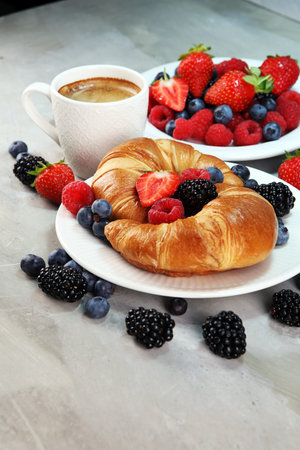 Delicious breakfast with fresh croissants and ripe berries on old marble background