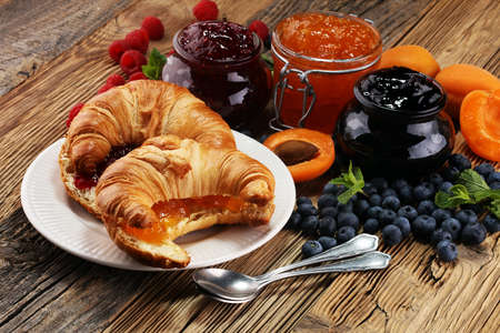croissants with marmalade and assortment of jams, seasonal berries, apricot, mint and fruits.の写真素材