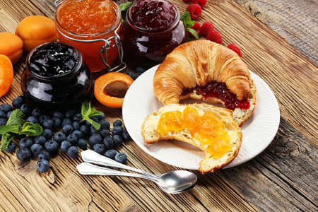 croissants with marmalade and assortment of jams, seasonal berries, apricot, mint and fruits.の写真素材