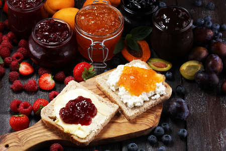 Toast bread with homemade strawberry jam and apricot marmalade on rustic table served with butter for breakfast or brunch.の写真素材