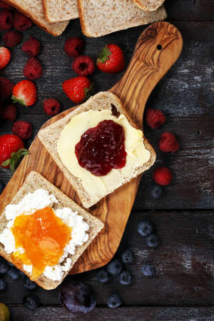 Toast bread with homemade strawberry jam and apricot marmalade on rustic table served with butter for breakfast or brunch.の写真素材