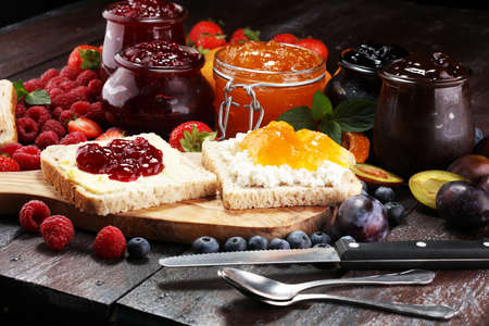 Toast bread with homemade strawberry jam and apricot marmalade on rustic table served with butter for breakfast or brunch.の写真素材