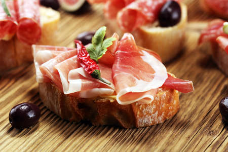 Sandwich with prosciutto or salami or crudo. Antipasti gourmet bruschetta snackの写真素材