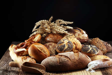 Different kinds of bread and bread rolls on board from above. Kitchen or bakery poster design.の写真素材