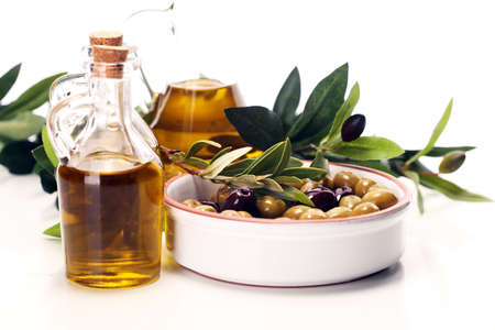 Bottle virgin olive oil and oil in a bowl with some olives.の写真素材