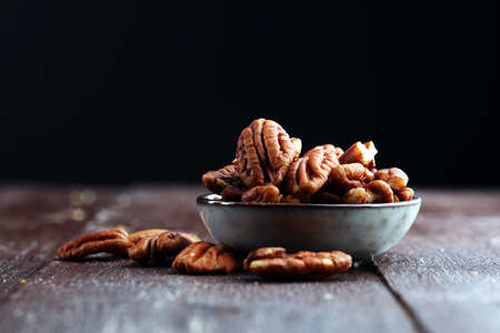 Pecan nuts on a rustic wooden table and pecan nuts in bowl.の写真素材