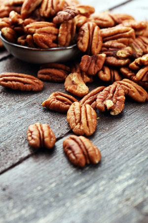 Pecan nuts on a rustic wooden table and pecan nuts in bowl.の写真素材
