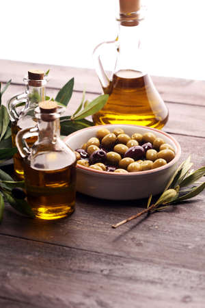 Bottle virgin olive oil and oil in a bowl with some olives.の写真素材