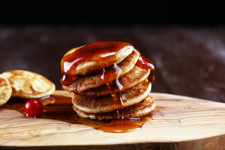 Pancakes with berries and maple syrup on rustic table.