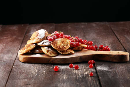 Pancakes or puffertjes with berries and maple syrup on rustic table.の写真素材