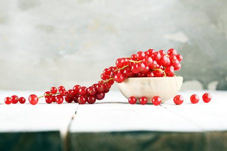 Fresh red currants on light rustic table. Healthy summer fruits.