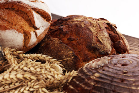 Different kinds of bread and bread rolls on board from above. Kitchen or bakery poster design.