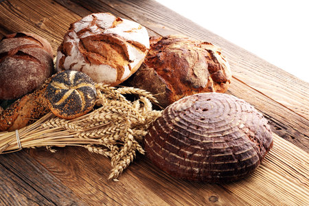 Different kinds of bread and bread rolls on board from above. Kitchen or bakery poster design.