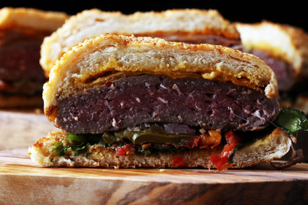 Cut in half angus burger on grain bun with tomato relish, lettuce and cheddar