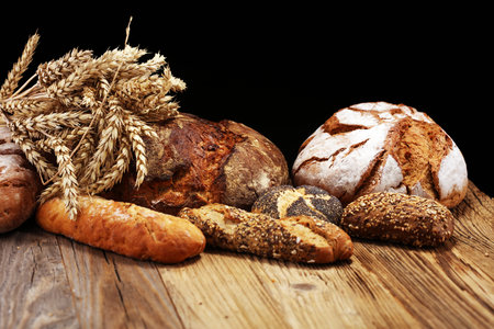 Different kinds of bread and bread rolls on board from above. Kitchen or bakery poster design.