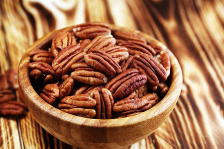 Pecan nuts on a table and pecan nuts in bowl.