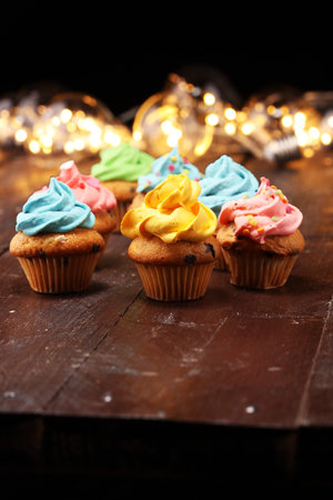 Tasty cupcakes on christmas winter background. Birthday cupcake in rainbow colors