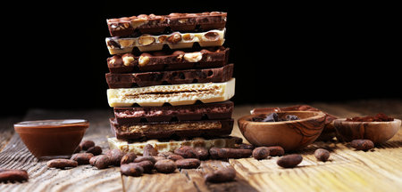 Chocolate bars on table with chocolate tower. Chocolate and nuts