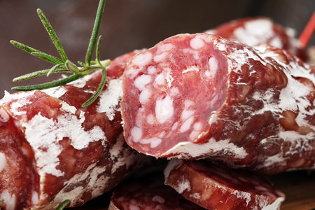 thinly sliced salami on a wooden texture on the background