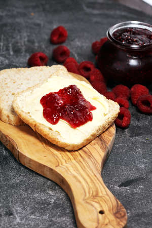 Toast bread with homemade raspberry jam or marmalade on rustic table served with butter for breakfast or brunch.の写真素材