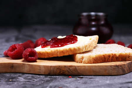 Toast bread with homemade raspberry jam or marmalade on rustic table served with butter for breakfast or brunch.の写真素材