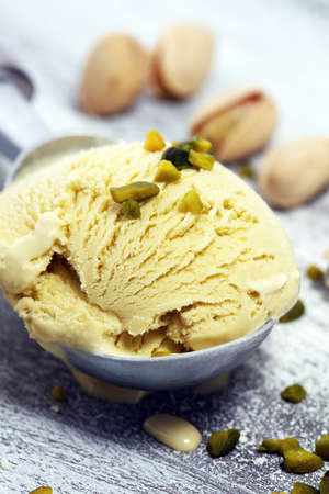 Pistachio ice cream scoop with chopped nuts and white chocolate on a rustic backgroundの写真素材