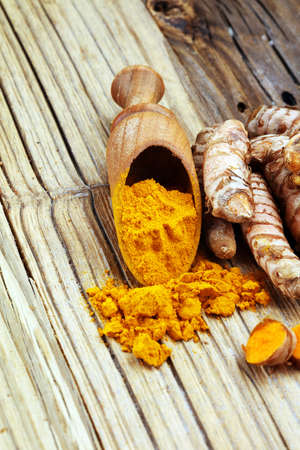 Turmeric powder and fresh turmeric on rustic background.の写真素材