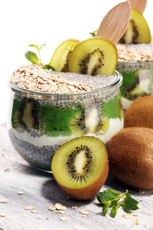 Healthy breakfast. chia pudding with kiwi and granola in glass on rustic backgroundの写真素材