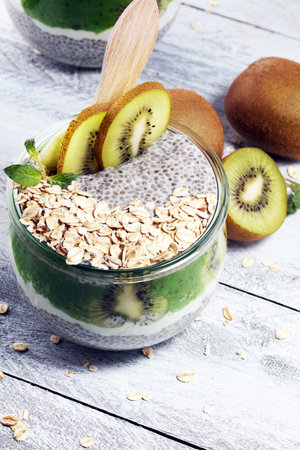 Healthy breakfast. chia pudding with kiwi and granola in glass on rustic backgroundの写真素材