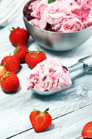 Strawberry ice cream scoop with chopped nuts and white chocolate on a rustic backgroundの写真素材