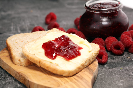 Toast bread with homemade raspberry jam or marmalade on rustic table served with butter for...